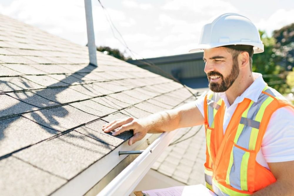A worker in an orange vest and hard hat is engaged in roofing tasks in Honolulu, highlighting the importance of safety.